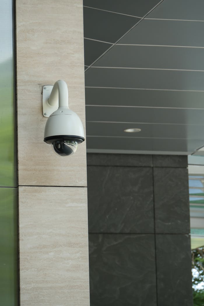 Close-up of a mounted security camera on a modern building's exterior.
